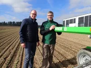v.li.: Landwirte Michael Wimmer und Stefan Allinger posieren für ein Foto vom Verein Waldleben auf ihrem Korianderfeld neben einem Landwirtschaftsroboter