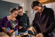 Ivo (Jakob D'Aprile, re.) übt für eine komplizierte Nierentransplantation. Olli (Arne Kertész, mi.) und Sofia (Olivia Papoli-Barawati, li.) fragen sich - muss das in der WG-Küche sein?