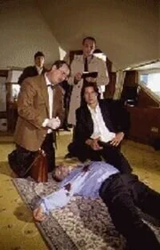 Gerichtsmediziner Dr. Leo Graf, Assistent Stockinger und Kommissar "Richie" Moser untersuchen den ermordeten Klaus Schuhmann.