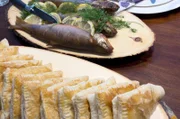 Im kalten Finnland bereiten Tuija und ihr Mann ein leckeres Gericht zu: geräucherte Forellen und Blätterteigtaschen mit Rentierfleischfüllung.