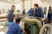 Aufregung im Möbelkombinat - ein großer Auftrag ist in Arbeit und eine Fräse ist ausgefallen. Martin (Florian Lukas, l.) und Maik Hüne (Aram Tafreshian, r.) haben alle Hände voll zu tun.