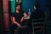 Lorenzo (Giacomo Giorgio, l.) sitzt in seiner Wohnung am Küchentisch und hat Besuch von einem Bekannten (Komparse).