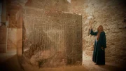 Ein Mann steht neben einer antiken Skulptur in Ägypten.