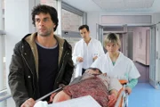 Die schwer verwundete Sophie (Isabell Polak, lieg.) wird von Dr. Mehdi Kaan (Kai Schumann, l.) ins Krankenhaus eingeliefert und von Dr. Marc Meier (Florian David Fitz) und Schwester Gabi (Annette Strasser) in Empfang genommen.