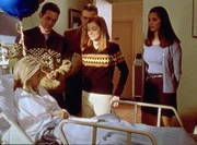 Buffy (Sarah Michelle Gellar, vorne) bekommt im Krankenhaus Besuch von ihren Freunden. V.l.: Xander (Nicholas Brendon), Giles (Anthony Stewart Head), Willow (Alyson Hannigan) und Cordelia (Charisma Carpenter) überbringen ihr Geschenke und wünschen ihr gute Besserung.