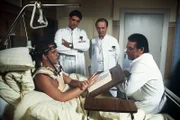 Die Fortschritte bei der Genesung von Tobias (Sven Jürgen Hasper, l.) lösen bei den Ärzten Dr. Udo Brinkmann (Sascha Hehn, 2.v.l.), Dr. Römer (Horst Naumann, 2.v.r.) und Prof. Brinkmann (Klausjürgen Wussow, r.) Erstaunen aus. Einen solchen Patienten hatten sie noch nicht.
