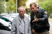 Der stadtbekannte Kleinkriminelle Hansen-Hansen (Thomas Neumann, l.) schlendert auffällig unauffällig über einen Parkplatz und probiert aus, welcher Wagen zu seinem "gefundenen" Schlüssel passt. Pech nur, dass er dabei von Polizist Lars Pöhlmann (Dominic Boeer, r.) erwischt wird.
