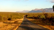 A road in the center of the desert leading to the mountains.