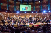 DAS KONZERT MIT DER MAUS - EDVARD GRIEG, Die Maus lädt zusammen mit Jana Forkel und Johannes Büchs (vorn, l) zu einem ganz besonderen Konzert ein, das die Herzen von Jung und Alt höher schlagen lässt! In der Kölner Philharmonie wird das Meisterwerk des norwegischen Komponisten Edvard Grieg vom WDR Sinfonieorchester unter der Leitung von Jesko Sirvend vor 1.800 Kindern zum Leben erweckt.