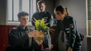 Kris (Marc Barthel, M.) und Isa (Lilli Hollunder) sind skeptisch: Wie soll diese Pflanze Johannes Berendsen (Nathan Goldblat, l.) entlasten?