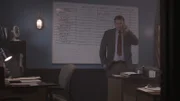 A man is on the phone in front of a white board.