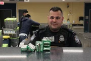 Officer Graham sitzt an seinem Schreibtisch und recherchiert, was das Medikament vor ihm ist. (National Geographic/Lucky 8 TV)