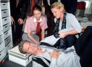 Das kommt davon: Weil Dr. Schmidt (Walter Sittler, lieg.) sich nicht anschnallen wollte, hat es ihn bei Turbulenzen heftig erwischt. Nikola (Mariele Millowitsch, re.) muss helfen. (li. Sylvia Esch als Stewardess)