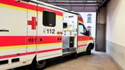E5 - An ambulance whit open sliding door in a garage. It belongs to the German Red Cross. The emergency call number is to be seen.