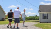 Host David Bromstad (right) leads Scott Danner (center) and Martha Danner (left) towards House 3, Mirimichi Meadow, Hero, as seen on My Lottery Dream Home, Season 16.