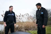 Sean Cobley (Anthony Flanagan, l.) und Kollege Troy Drakes (Divian Ladwa, r.) stehen vor einer schwierigen Entscheidung: Sollen sie den Koffer öffnen?