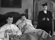 Stan (Stan Laurel, links) und Oliver (Oliver Hardy) genießen das Studentenleben – und wissen nicht, dass sie es sich ausgerechnet im Bett des Dekans (Wilfred Lucas, stehend rechts)