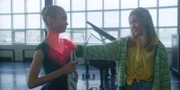 Jade (Georgia Pemberton, r.) klopft einer jungen Balletttänzerin (Komparsin, l.) lobend auf die Schulter. In Wahrheit kopiert sie deren exzellentes Tanzkönnen mit ihren magischen Kräften, um später in ihrer eigenen Ballettklasse zu glänzen.