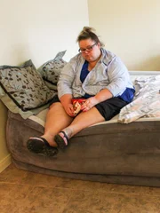 Brianne sits on bed