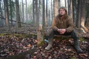 Gerrid ruht sich auf einem Baumstumpf im Wald aus.