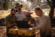 Max, Colin, Chris & Ramon looking at laptop on dig site.