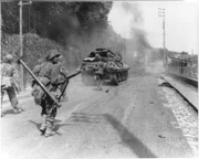 Amerikanische Truppen bewegen sich auf dem Weg nach Paris in Richtung Fontainebleau, während der Rauch von gesprengten deutschen Panzern den Himmel erfüllt.