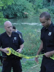 Police set up a crime scene after finding a dead body in a river.