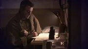 Ein Mann sitzt an einem Schreibtisch und liest ein Dokument