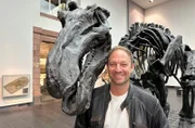 Moderator Tobis Kämmerer mit einem Dino im Senckenberg Museum in Frankfurt am Main.