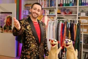 Ein Modedesigner (Marti Fischer) präsentiert Jan und Henry seine Kollektion.