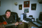 "Croppie" und ehemaliger Frontmann der Troggs übt seine Gitarre vor seinen Paltinum-Platten.