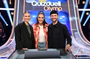 Moderatorin Esther Sedlaczek (M.) mit den Kandidat:innen des Teams "Glasperlen": der Musikerin Carolin Niemczyk (l.) und dem Musiker Daniel Grunenberg (r.).