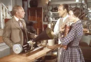 Mr. Oleson (Richard Bull, M.) und Mrs. Oleson (Katherine McGregor, r.) wissen nicht so recht, was sie mit Mr. Godfreys (George Furth, l.) Sprechmaschine anfangen sollen.