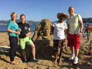Gruppenfoto mit Sandburg und Entertainment-Managerin Cori, dem Zweiten Offizier Christian, Reiseleiter Bernd und dem Vizeweltmeister im Sandburgenbauen.