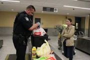 Officer Graham untersucht weiterhin die Lebensmittel aus der Transportkiste der Familie.