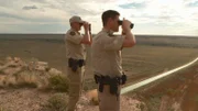 Aaron Sims and Stewart Rogers look through binoculars.