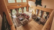 Looking down to the living room of the Silver Spruce Lodge from the second floor shows off the open space and high windows, as seen on Log Cabin Living.