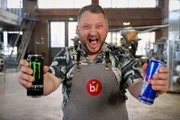 Sebastian Lege steht in seiner Werkstatt und hält zwei Getränkedosen in seinen Händen. Er schaut schreiend in die Kamera.