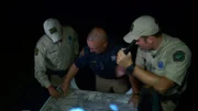 Trent Marker, Mike Stephens, and a Sherif look at a map with flashlights.