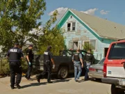Policemen walking to a house.