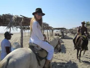Mitglied des Showensembles Esther auf einem Pferd am Strand, im Hintergrund reitet Kollege Adamo.