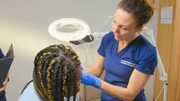Dr Emma examining Leonie Keloid. Nurse hand and laptop in background, left side