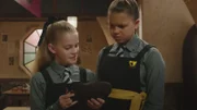 Esther (Jenny Richardson, l.) tauscht ihr Maglet – ein Tablet in der Hexenwelt – mit Maudes. Ihre Freundin Drusilla (Tallulah Milligan, r.) ist von dem Plan nicht überzeugt.