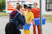 Maxi Schuster (Ada Philine Stappenbeck, l.) kann kaum von ihrem Handy aufschauen und übersieht dabei einen Pfahl. Kiran (Daniel Rodic, M.) und Fiete (Adrian Gössel, r.) fragen, ob sie sich verletzt hat?