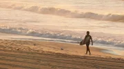 Einmal Sonne tanken. Wir sind unterwegs zu den schönsten Stränden der Welt. Von der Algarve bis zu den Seychellen - 20 Traumstrände, die Sie kennen sollten. - Surfer vor der Brandung.