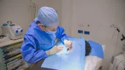 MS shot of DR Emma in scrubs performing an operation to remove Cavalli's keloids
