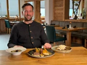 Krüner Stub'n in Krün: Wirt Maximilian Schandl stellt das Menü des Tages vor. Vorspeise: Essenz von der Bauernente, Crêpesroulade und Wurzelgemüse - Hauptgericht: Lammrücken mit Bohnen-Involtini und Selleriepüree - Nachtisch: Cheesecake mit Popcorn, Karamell und Eis.