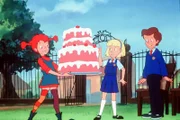 Pippi (l.) will dem Schulrat eine Erfrischung holen. Nachdem sie das ganze Buffet bis auf eine Torte selbst verschlungen hat, bringt Pippi diese mit nach draußen.