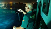 Ein Wachmann sucht mit einer Taschenlampe nach einem Boot.