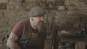 Stuart Prior in der Schmiedewerkstatt mit der nachgebildeten Pfeilspitze, die auf der in Siston entdeckten Pfeilspitze basiert.